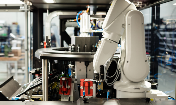 Automatisierte Fertigungszelle mit Industrieroboter und Rundschalttisch – esmo automation Weißer Roboterarm in moderner Produktionsanlage für automatisierte Montageprozesse